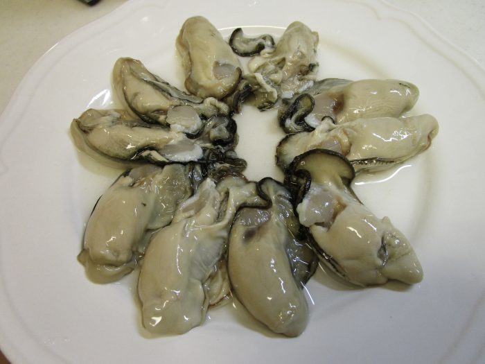 10個の生牡蠣を皿に並べている